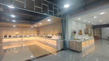 A spacious hotel lobby with a central reception desk, a seating area, and a decorative wall.