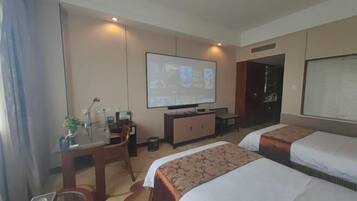 Habitació d'hotel amb un llit, un escriptori amb un ordinador, una televisió i una finestra.