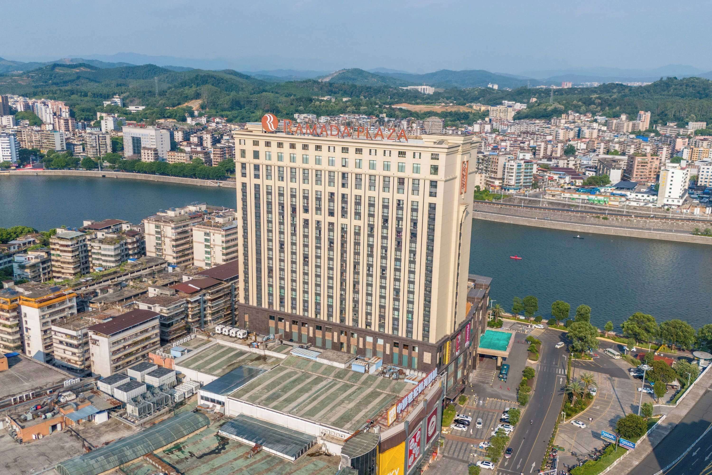 Um hotel moderno com vista para um rio e o horizonte urbano.