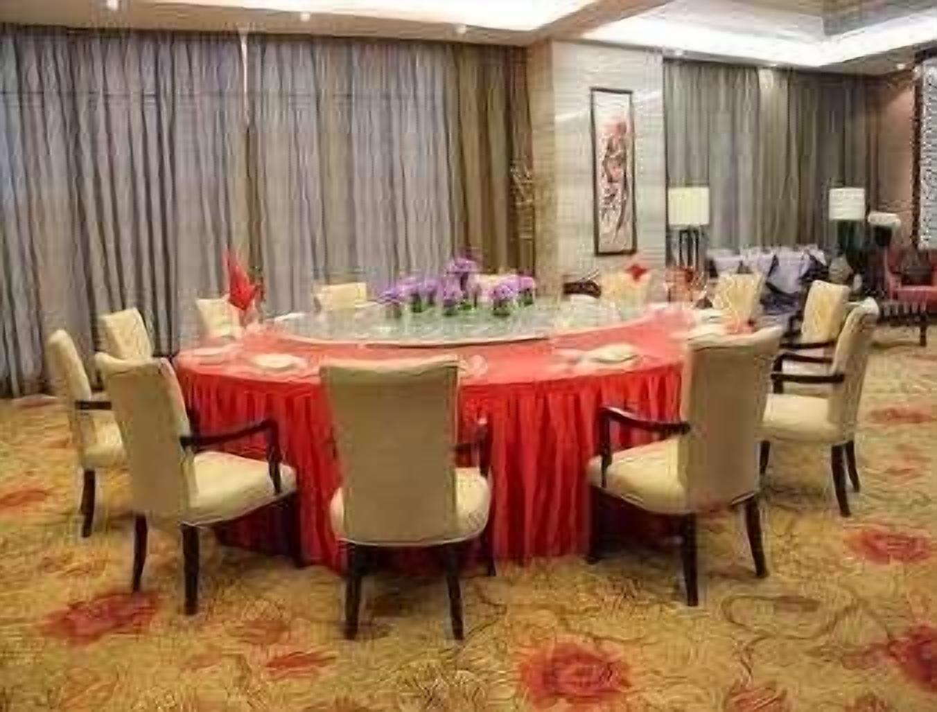 Een vergaderzaal met een ronde tafel, stoelen en een vloerbedekking.