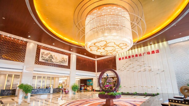 A spacious lobby with a large chandelier, a reception desk, and a decorative circular planter. - Ramada Plaza Shaoguan City Centre (Shaoguan)