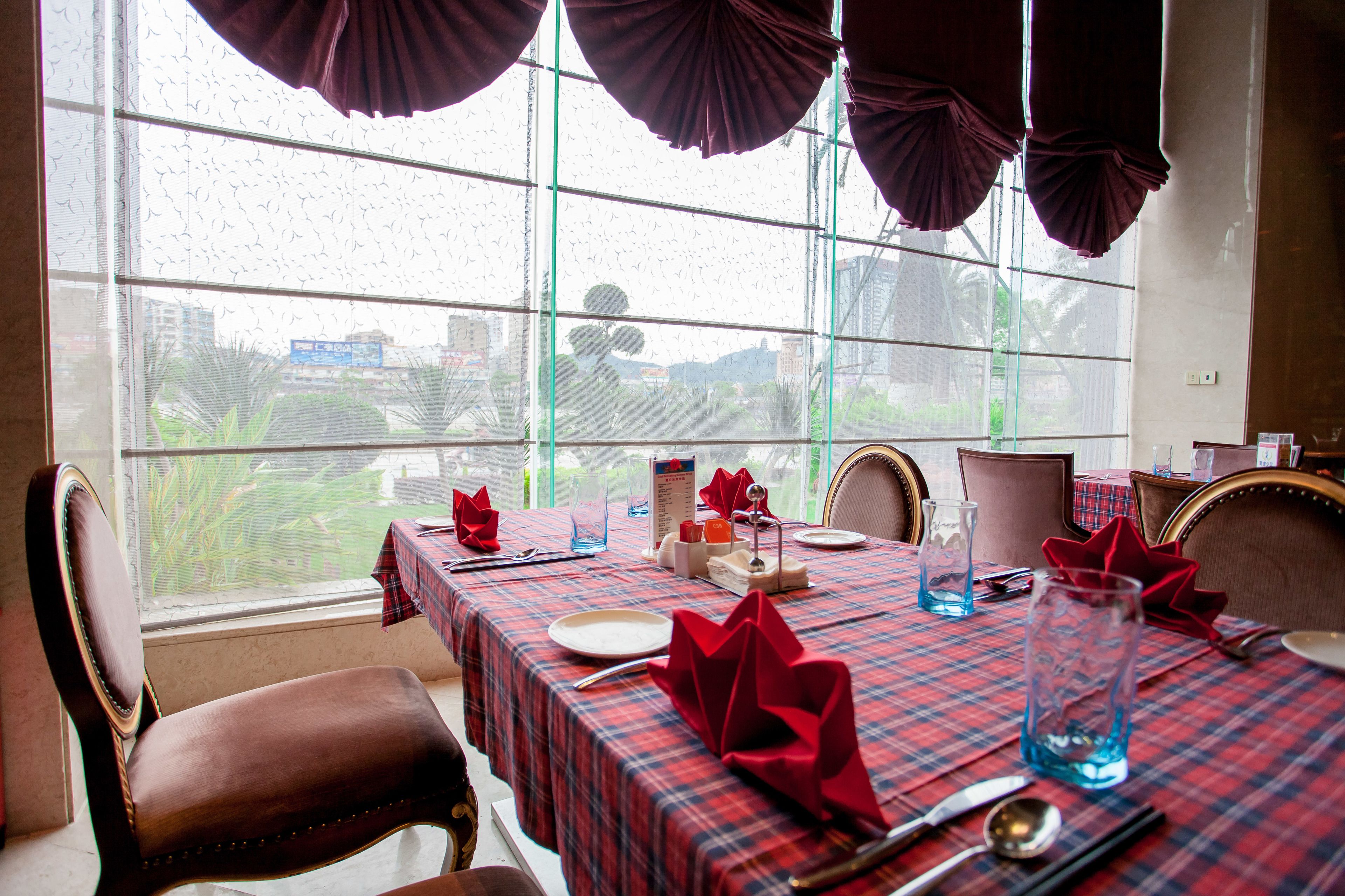 A dining area with a table set for four, featuring a plaid tablecloth, red napkins, and a blue glass pitcher.