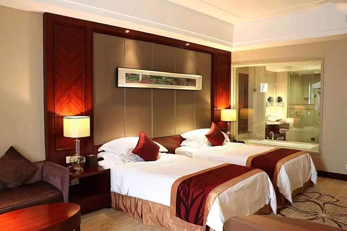 Habitación de hotel con dos camas, un sofá, un escritorio y un espejo grande.