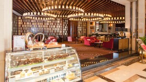 A hotel lobby with a central seating area, a reception desk, and a dessert display. - Ramada Plaza Shaoguan City Centre (Shaoguan)