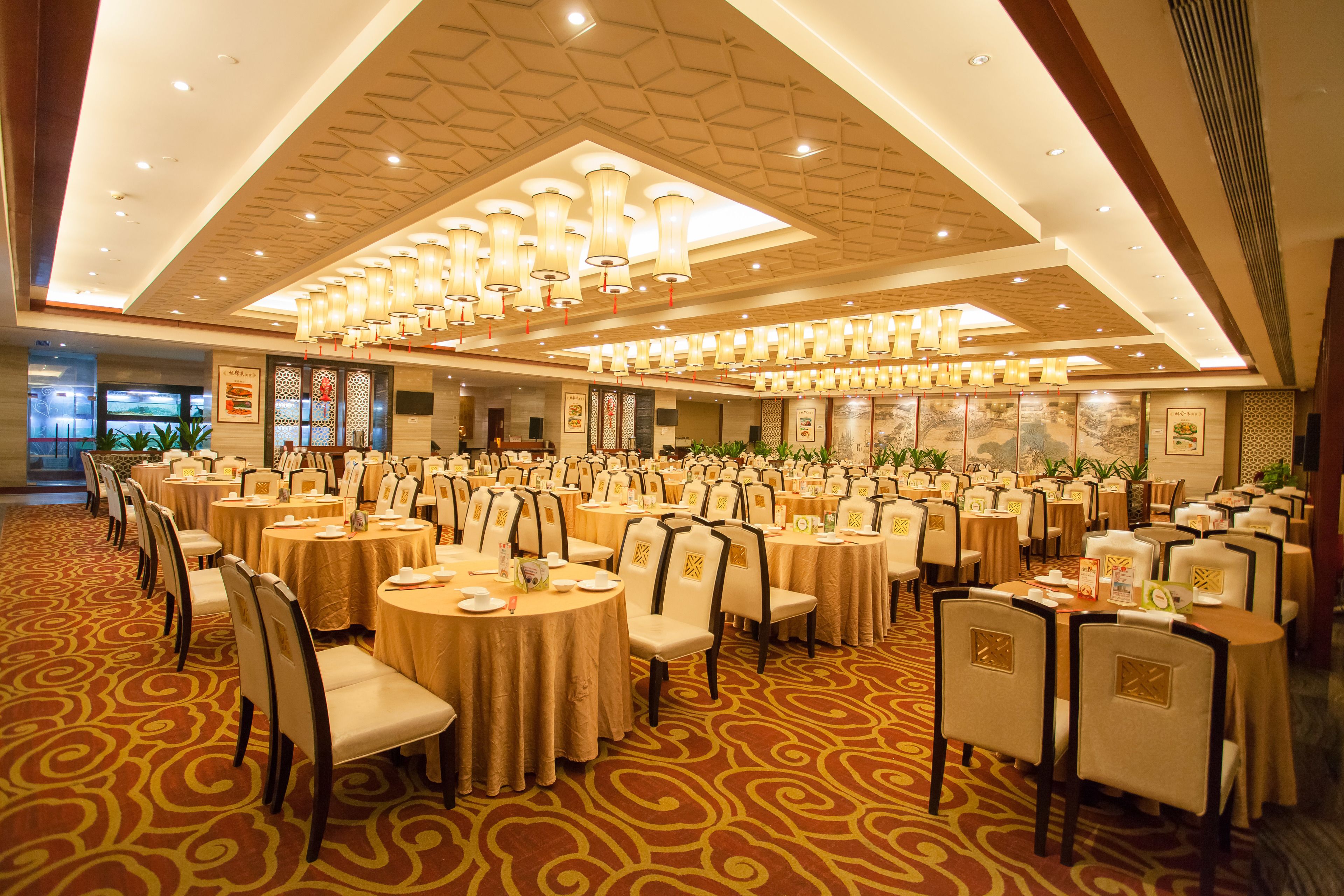 Une salle de banquet avec des tables rondes, des chaises et un tapis à motifs.