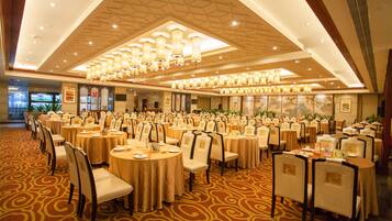 Une salle de banquet avec des tables rondes, des chaises et un tapis à motifs.