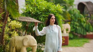 A person standing next to a large elephant statue in a lush garden setting.