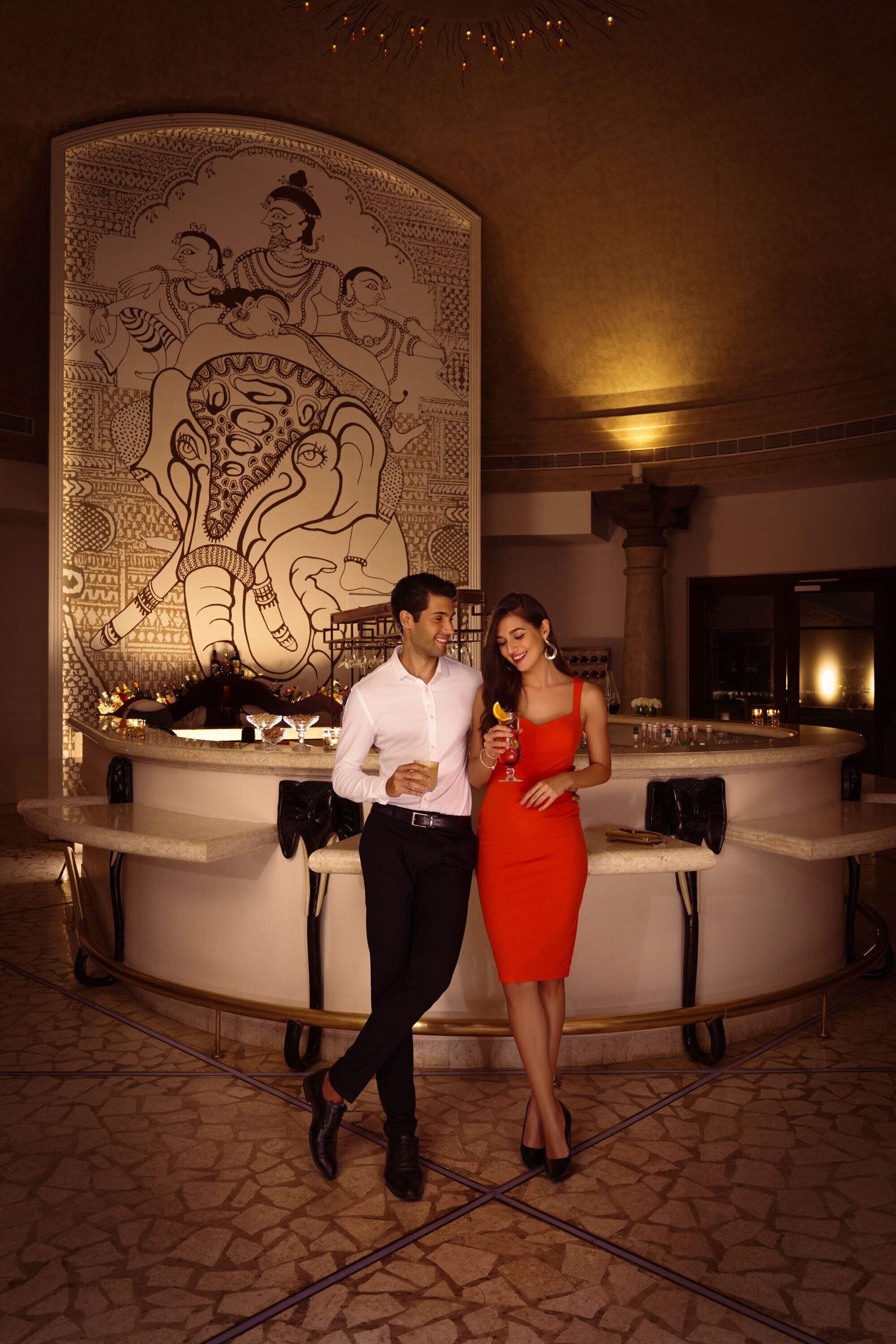 A bar area with a large decorative wall, a curved counter, and a tiled floor.