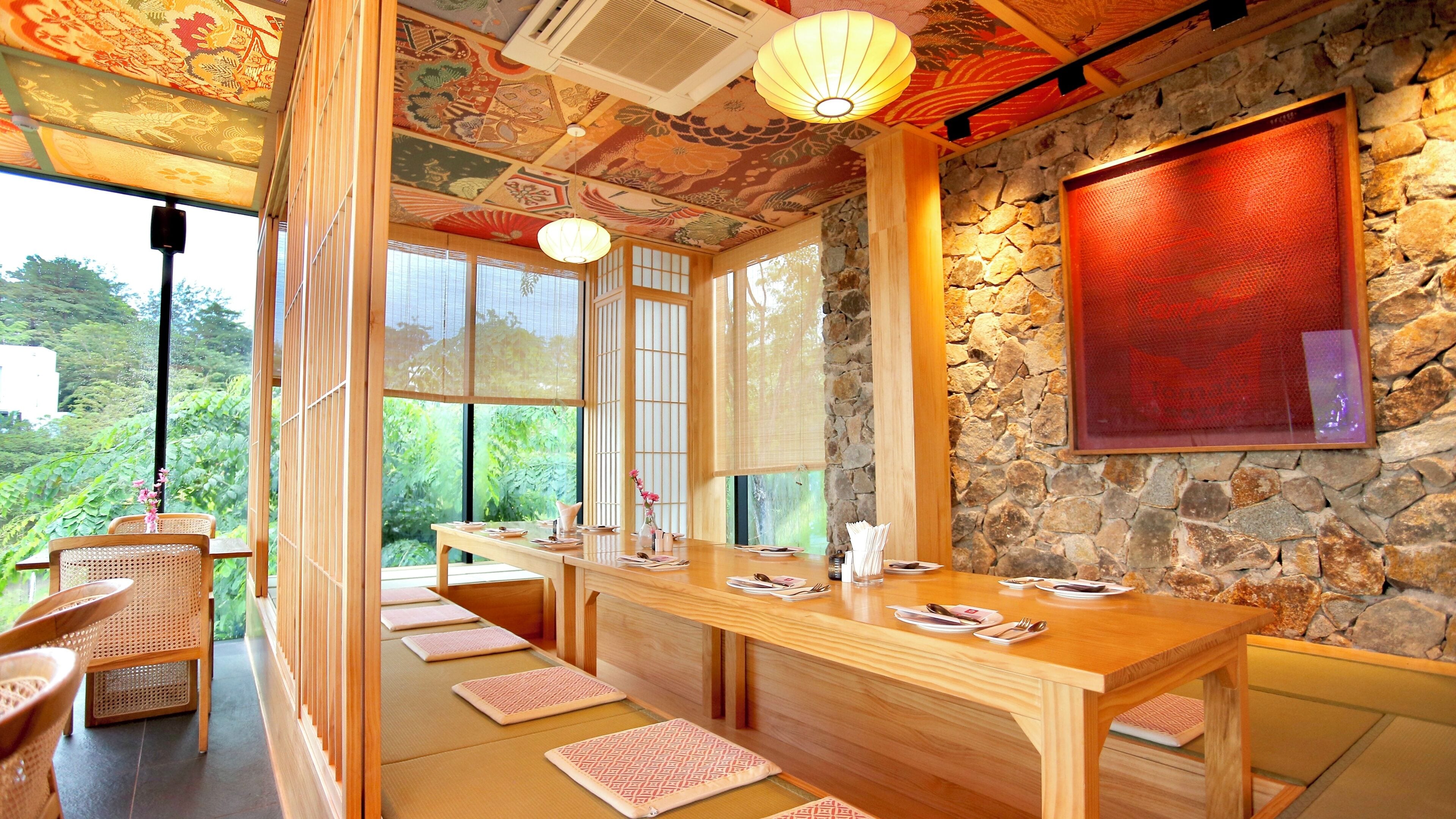 A traditional Japanese-style room with tatami mats, a wooden table, and a stone wall.