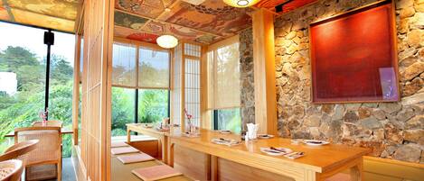 A traditional Japanese-style room with tatami mats, a wooden table, and a stone wall.