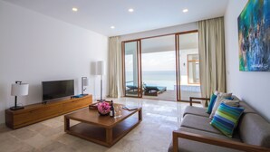 Uma sala de estar moderna com televisão de tela plana, mesa de centro de madeira e um sofá com almofadas coloridas.