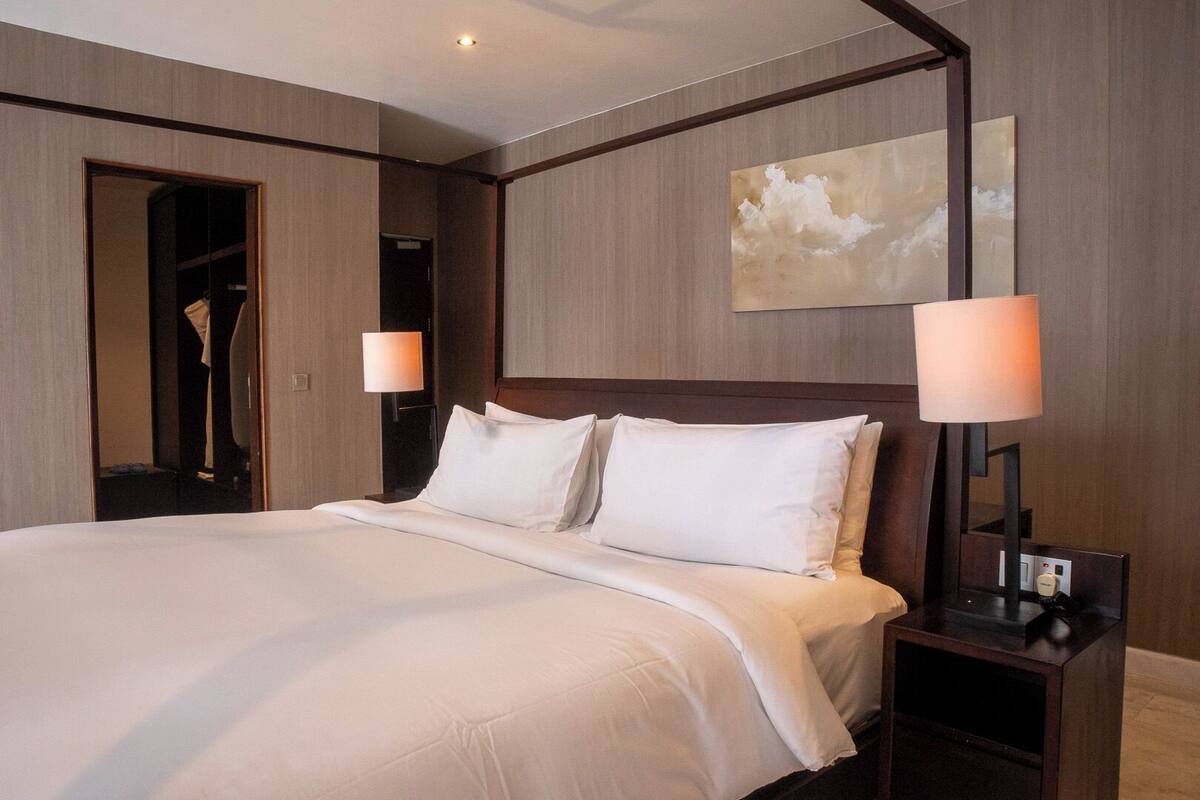 Ein Hotelzimmer mit einem großen Bett, zwei Nachttischlampen, einem Nachttisch und einem Bild an der Wand.