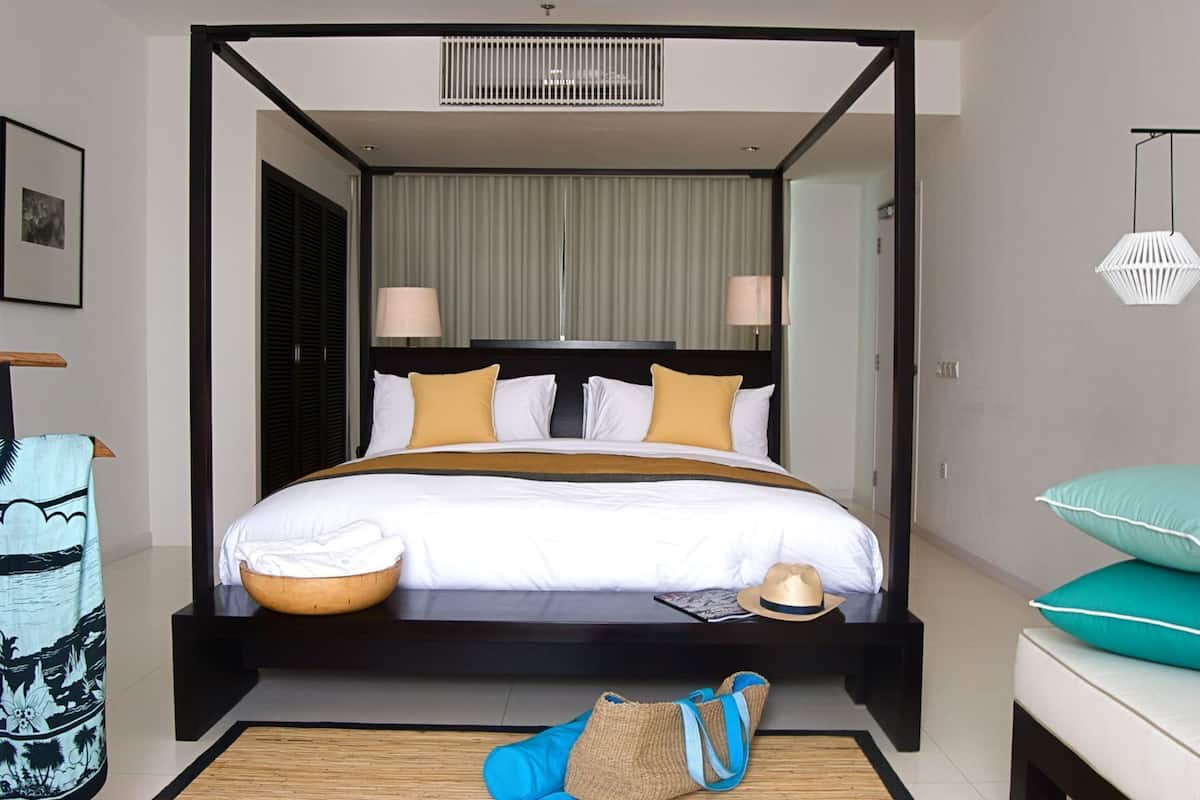 Ein Himmelbett mit schwarzem Gestell, weißer Bettwäsche und zwei Nachttischlampen.