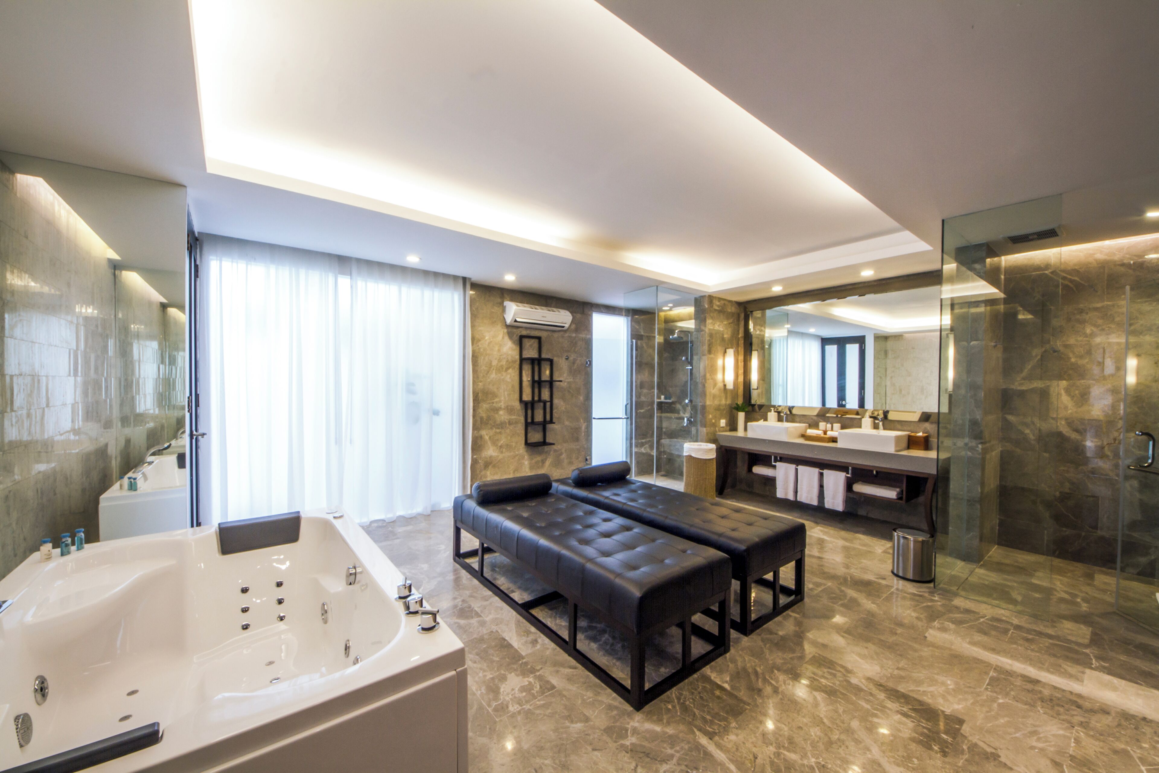 A modern bathroom with a large bathtub, a bench, a glass shower enclosure, and a vanity with a mirror.