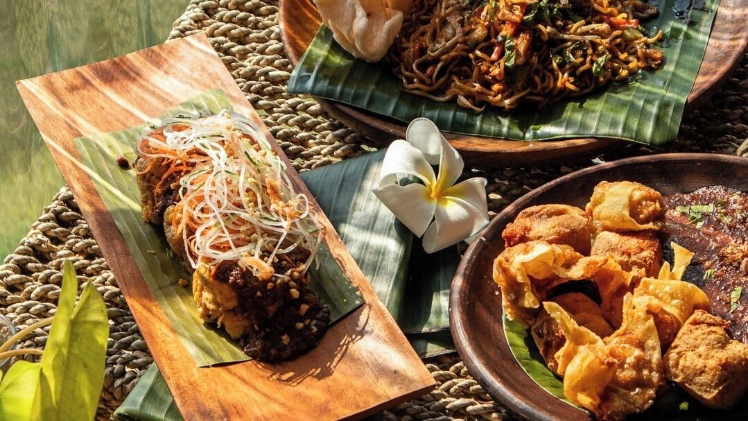 A variety of dishes on wooden and banana leaf plates, suggesting a meal setting.