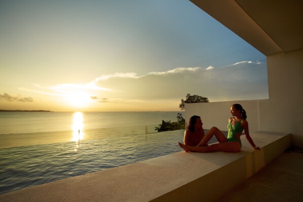 Two individuals sitting by a poolside at sunset. - Montigo Resorts Nongsa (Batam)