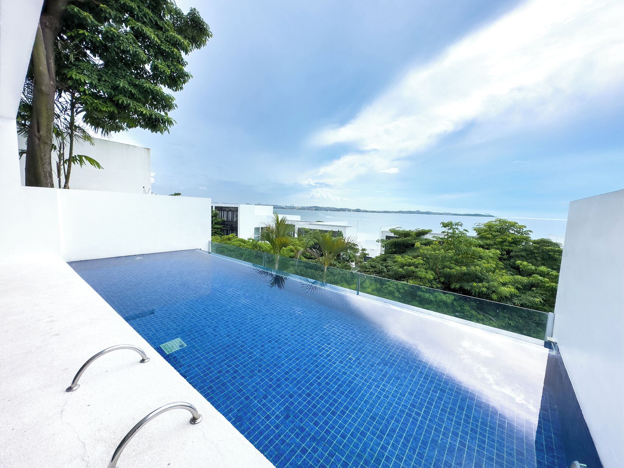 A modern infinity pool with a clear view of the sea and distant buildings.