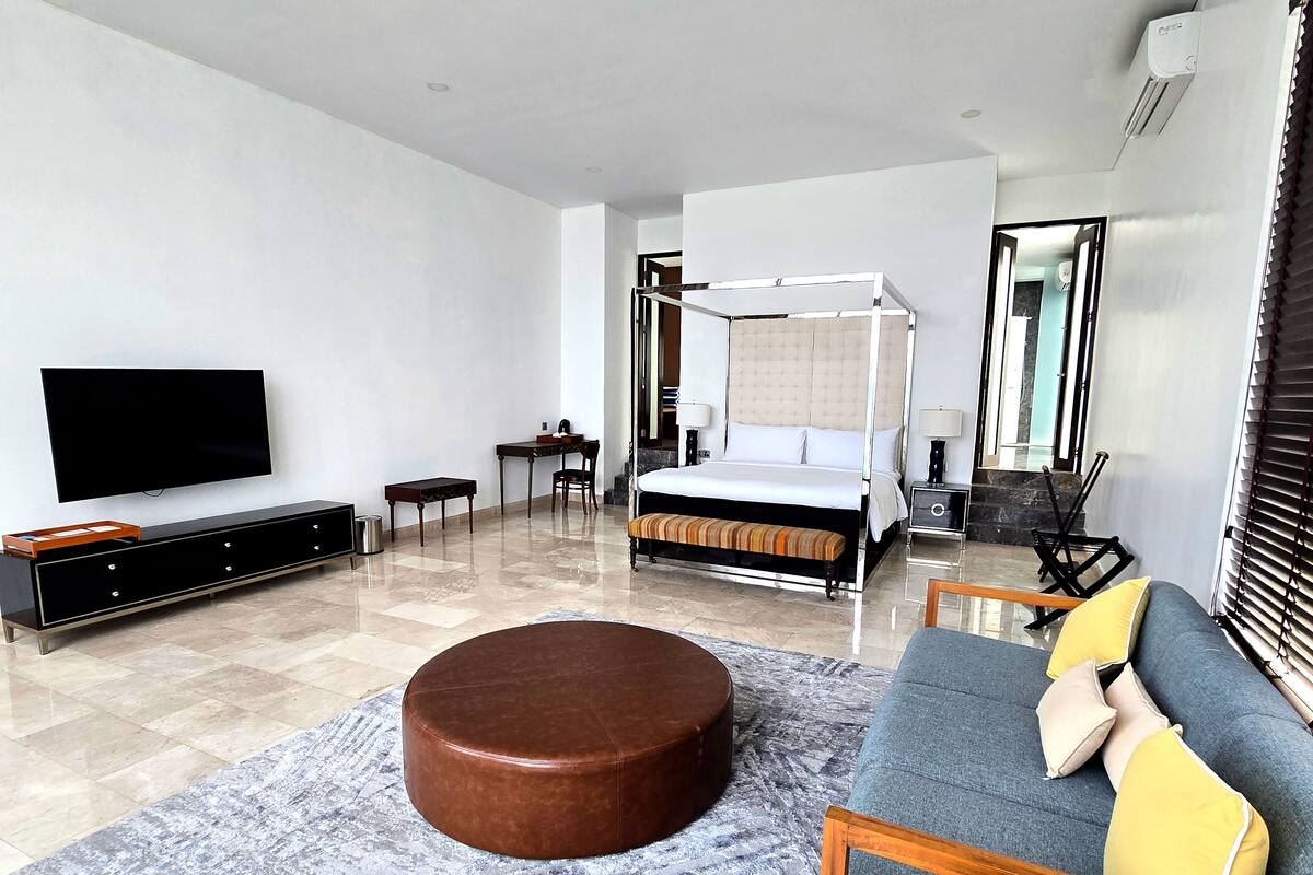 Ein modernes Hotelzimmer mit einem großen Bett, einem Fernseher, einem Schreibtisch und einer Couch.