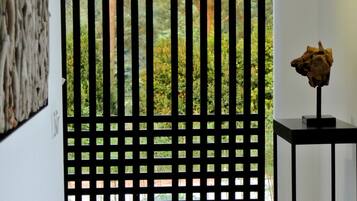 A room with a black lattice partition, a small table with a sculpture, and a textured wall.