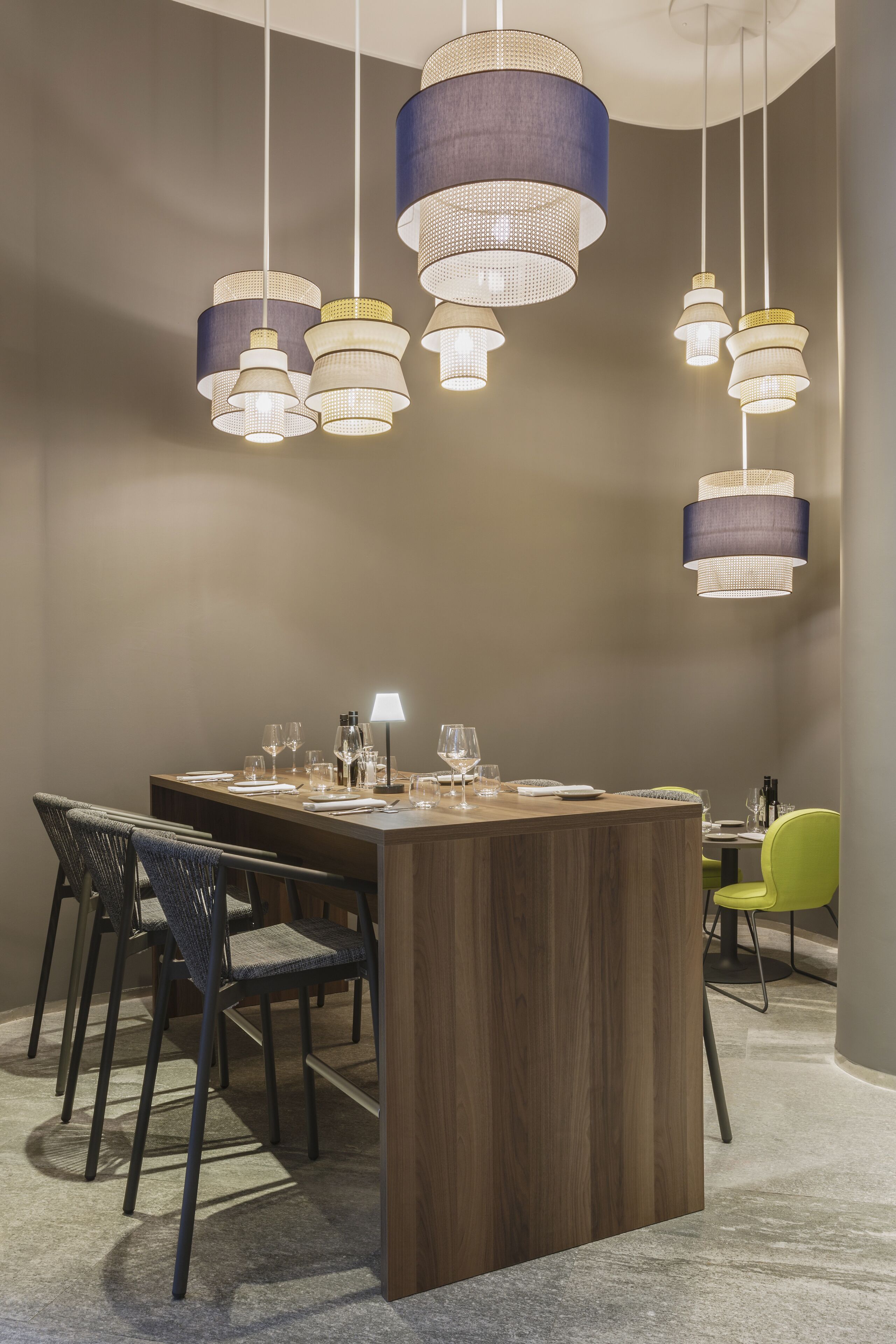 A modern dining area with a wooden table, chairs, and hanging pendant lights.