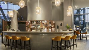 A modern bar area with a curved counter, multiple stools, and hanging pendant lights.