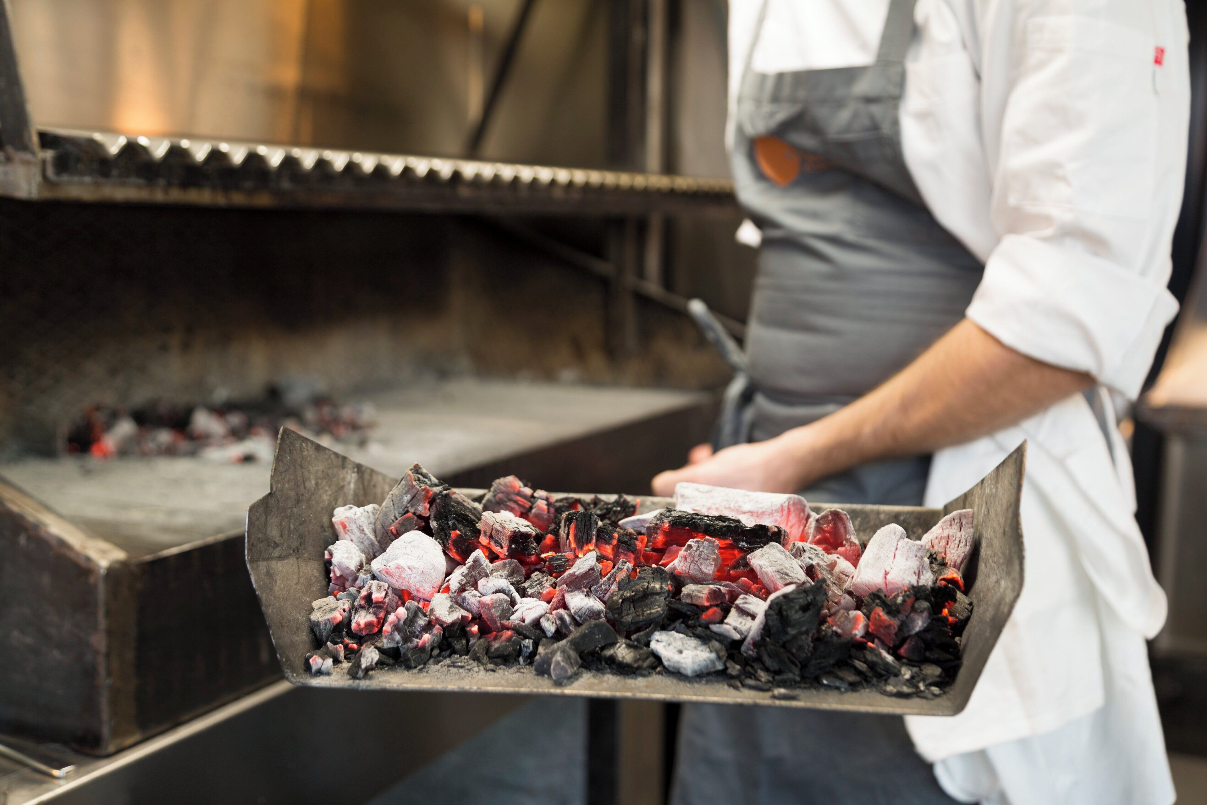 A chef handling a tray of charcoal.