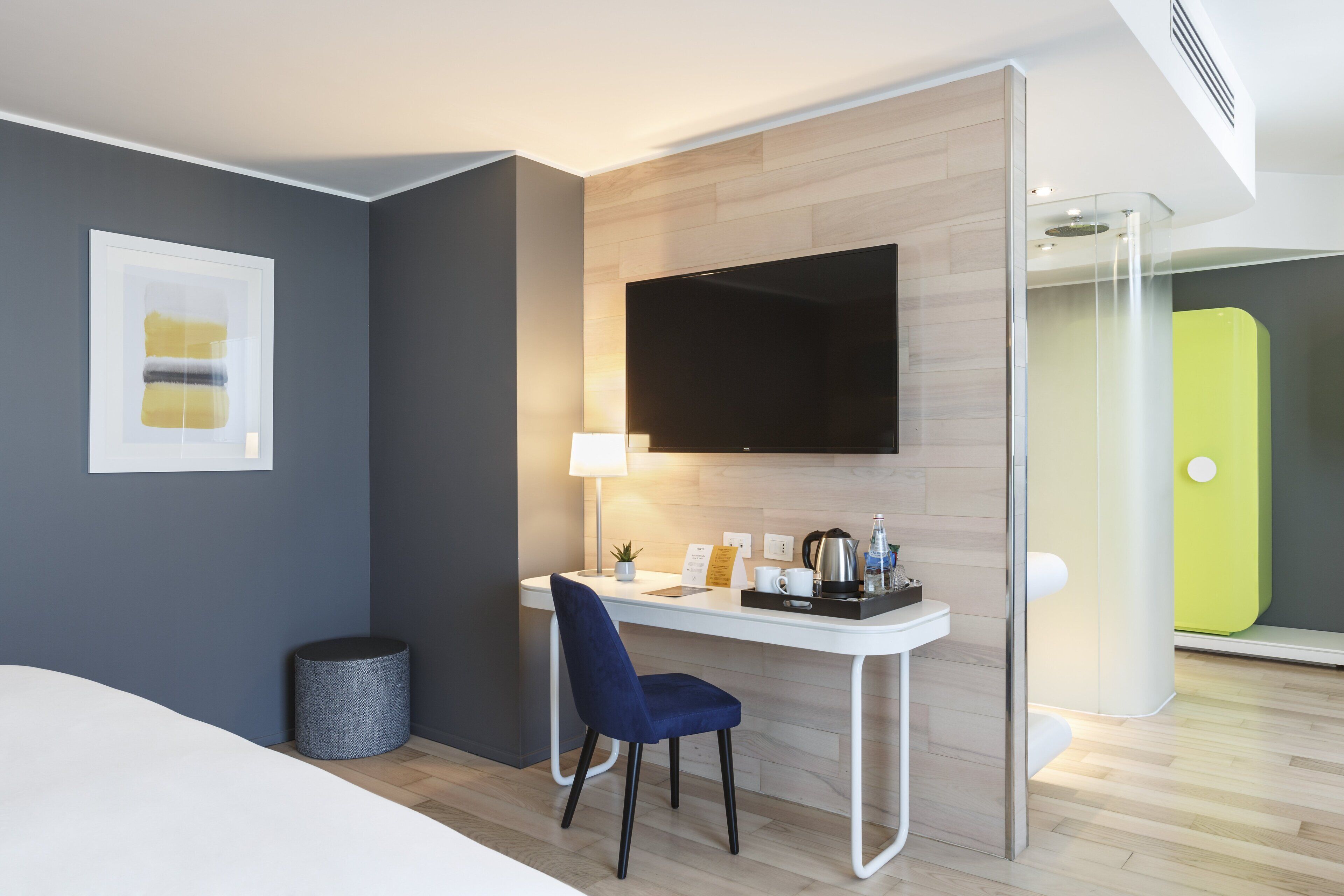 Een moderne hotelkamer met een bureau, stoel en een wandgemonteerde flatscreen televisie.