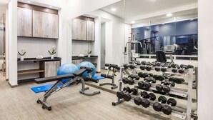 A modern gym with exercise equipment, a bench, and a rack of dumbbells. - NH Bogotá Urban 93 Royal (Bogotá)