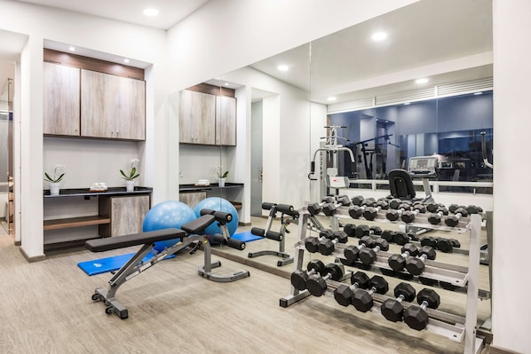 A modern gym with exercise equipment, a bench, and a rack of dumbbells. - NH Bogotá Urban 93 Royal (Bogotá)