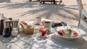 A beachside dining table with a menu, condiments, and a plate of food.