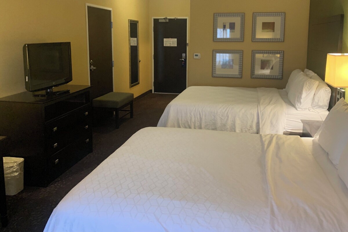 Een hotelkamer met twee bedden, een televisie, een bureau en een stoel.