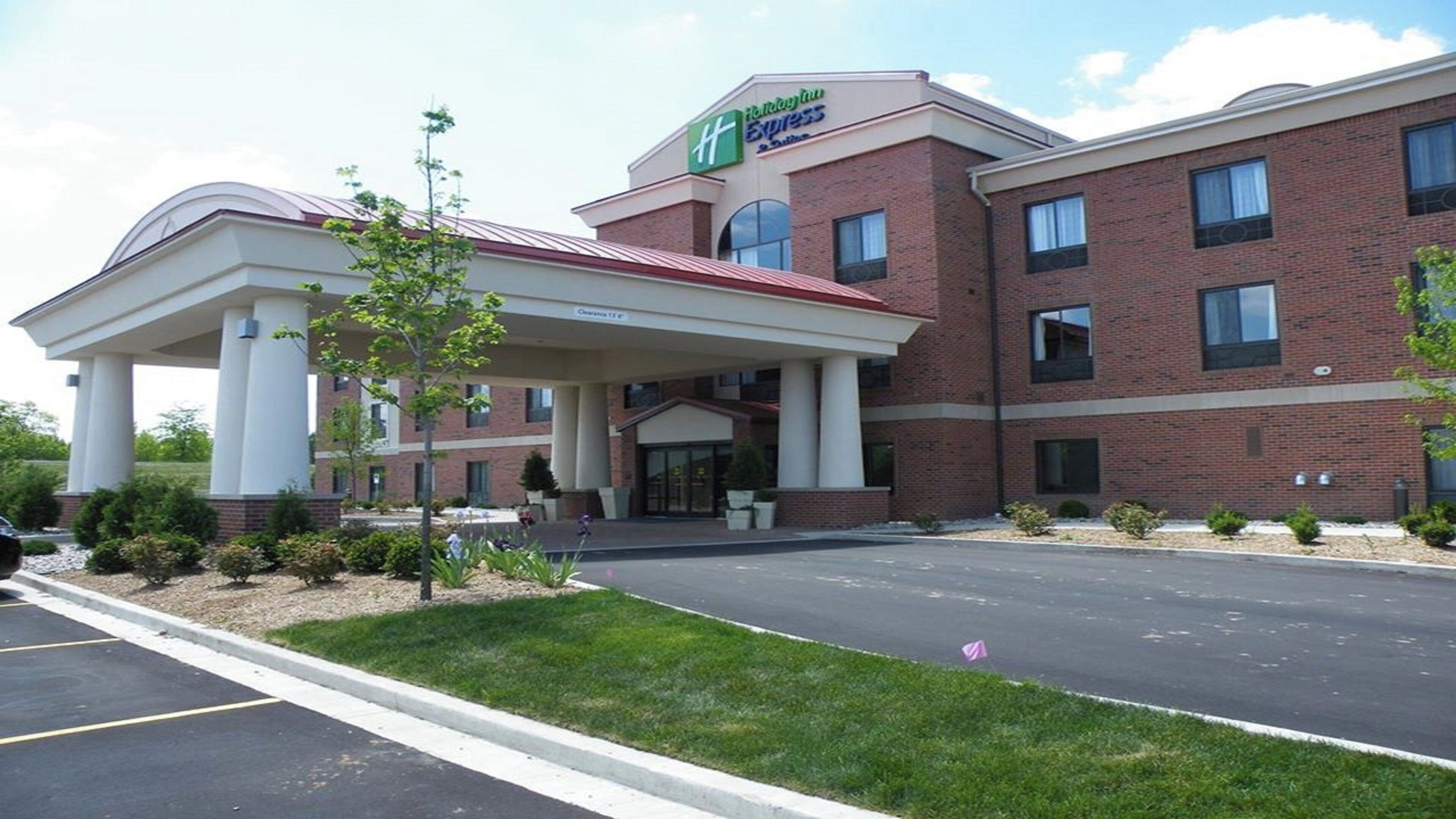 Un hotel Holiday Inn Express con entrada cubierta, fachada de ladrillo y estacionamiento.