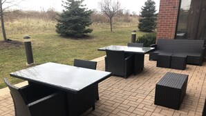 An outdoor patio area with a brick floor, featuring a table and chairs set up for dining.