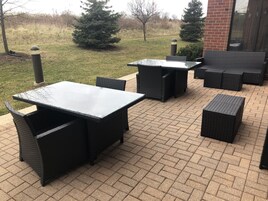 Un espacio de patio al aire libre con piso de ladrillo, con una mesa y sillas dispuestas para comer.