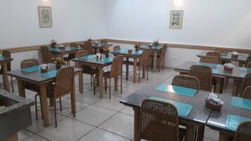 A dining area with tables and chairs, some with flower arrangements.