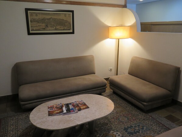 A room with two sofas, a small round table with magazines, a lamp, and a framed picture on the wall. - Hotel Ideal (Londrina)
