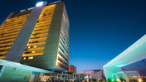A hotel with a pool area, outdoor seating, and a high-rise building in the background. - EPIC SANA Luanda Hotel (Luanda)