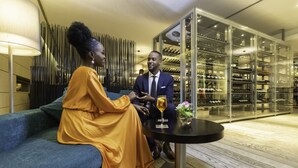 A modern interior with a sofa and a table, a wine rack, and a lamp. - EPIC SANA Luanda Hotel (Luanda)