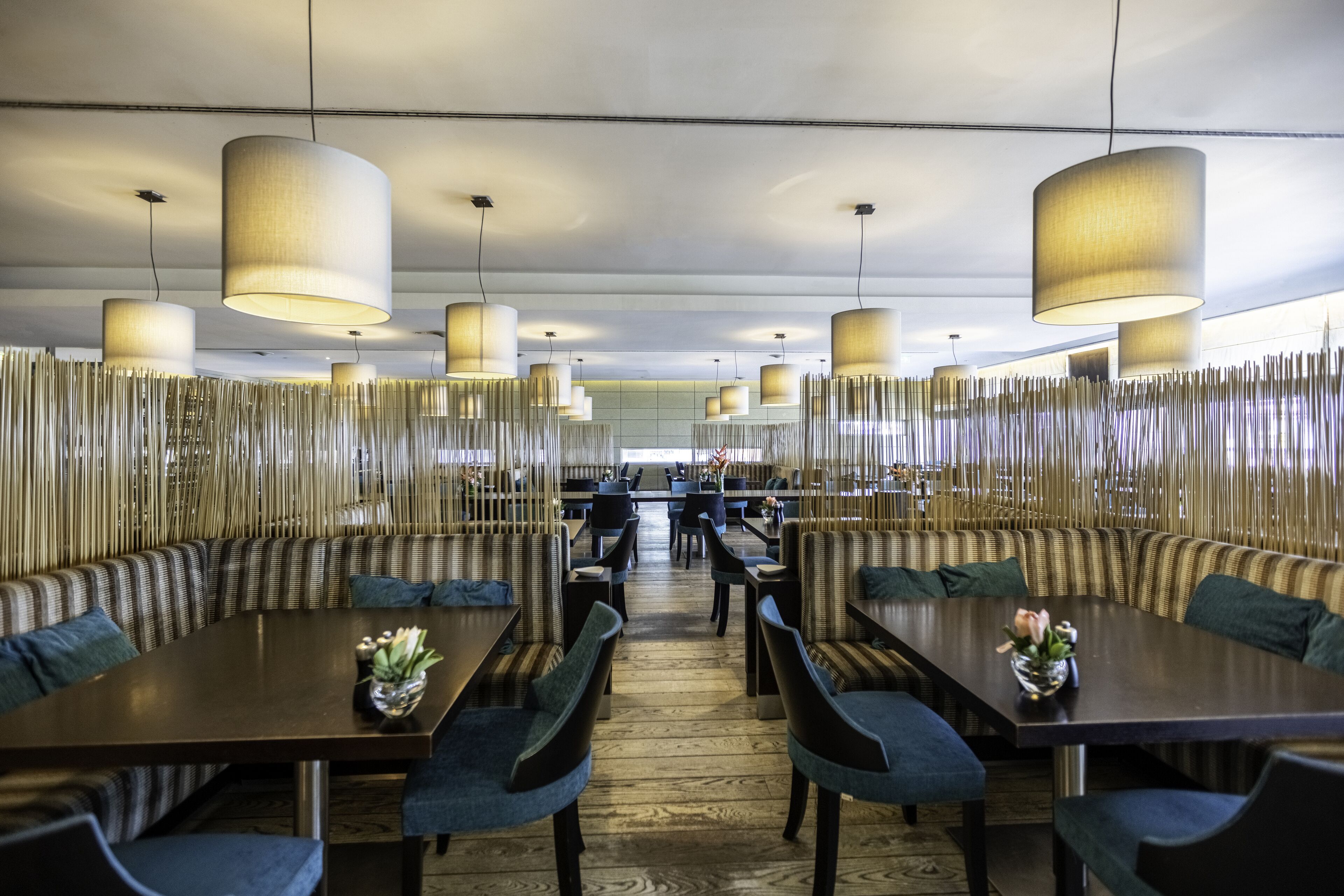 A modern dining area with high tables, chairs, and hanging lamps.