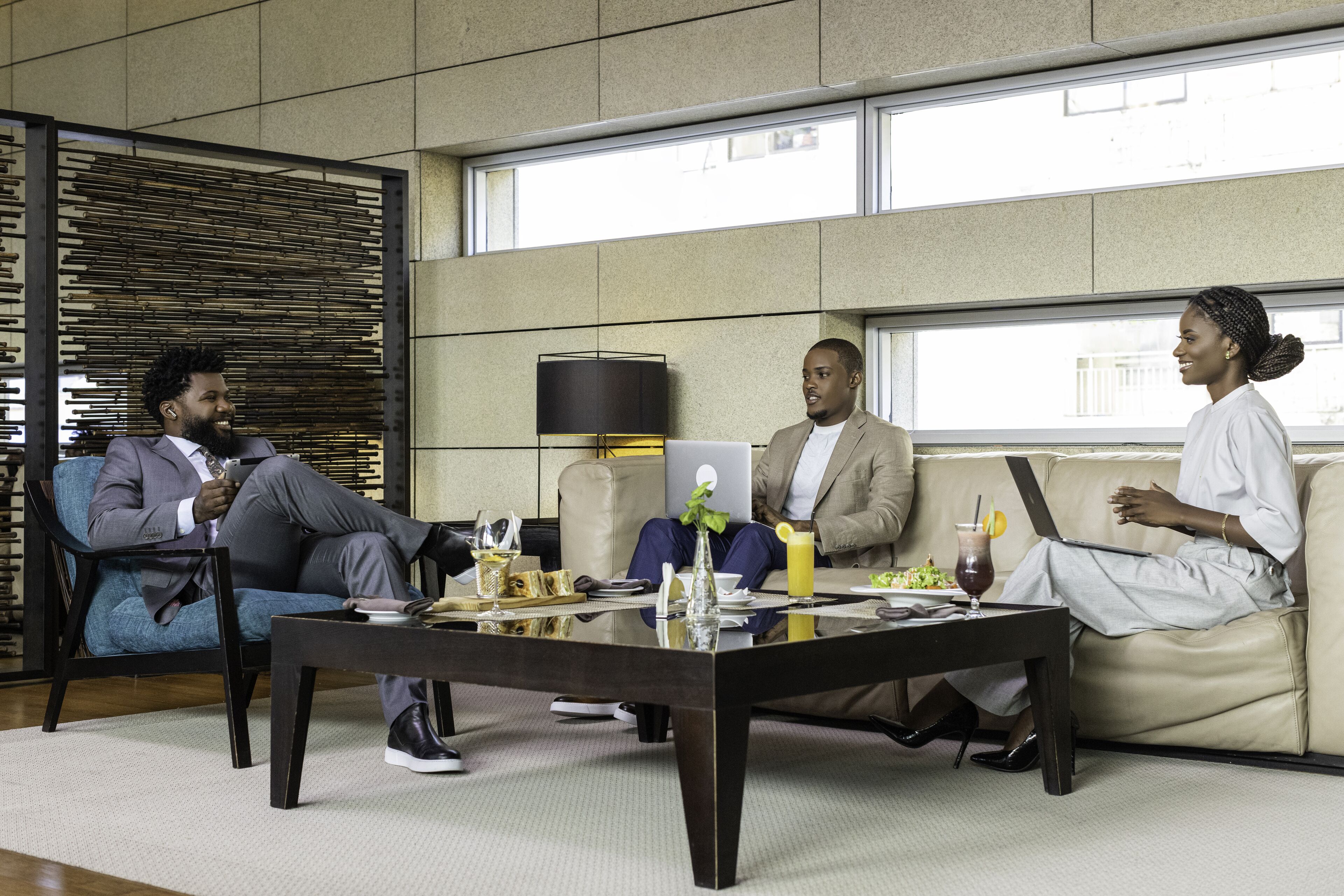 A modern meeting room with a glass coffee table, leather couches, and a large window.