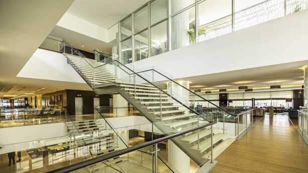 A multi-level interior with glass railings and wooden flooring, featuring a central staircase and open spaces. - EPIC SANA Luanda Hotel (Luanda)