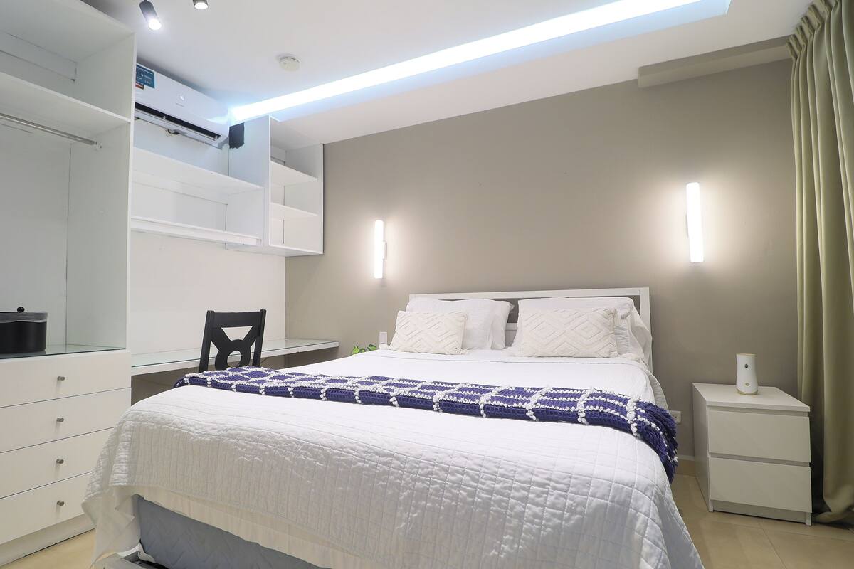 A bedroom with a bed, a nightstand, a chair, and a wardrobe.