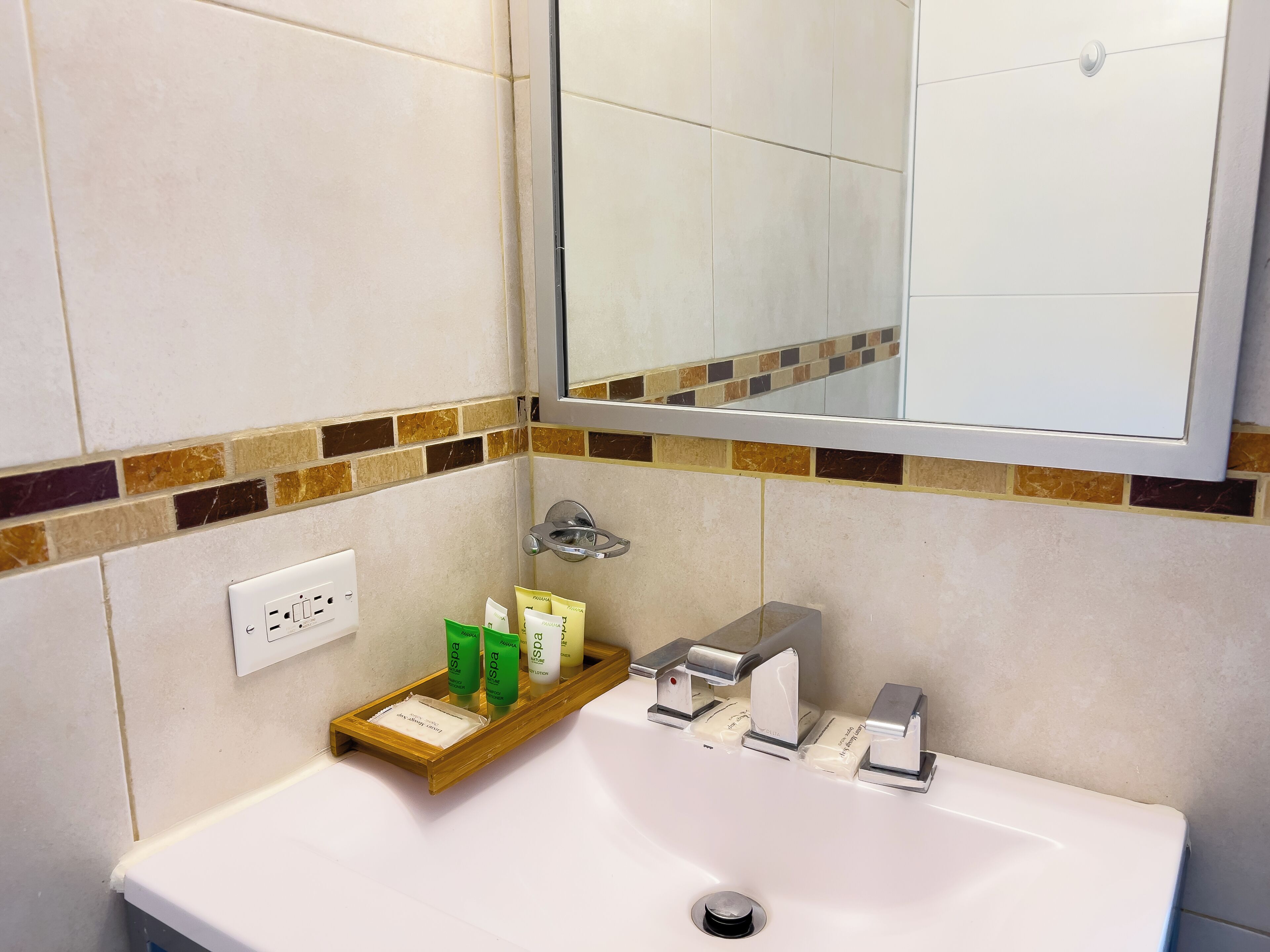 Un baño con un lavabo blanco, un espejo encima y un estante con artículos de aseo.