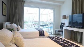 Habitación de hotel con dos camas, televisión y vista al puerto deportivo.