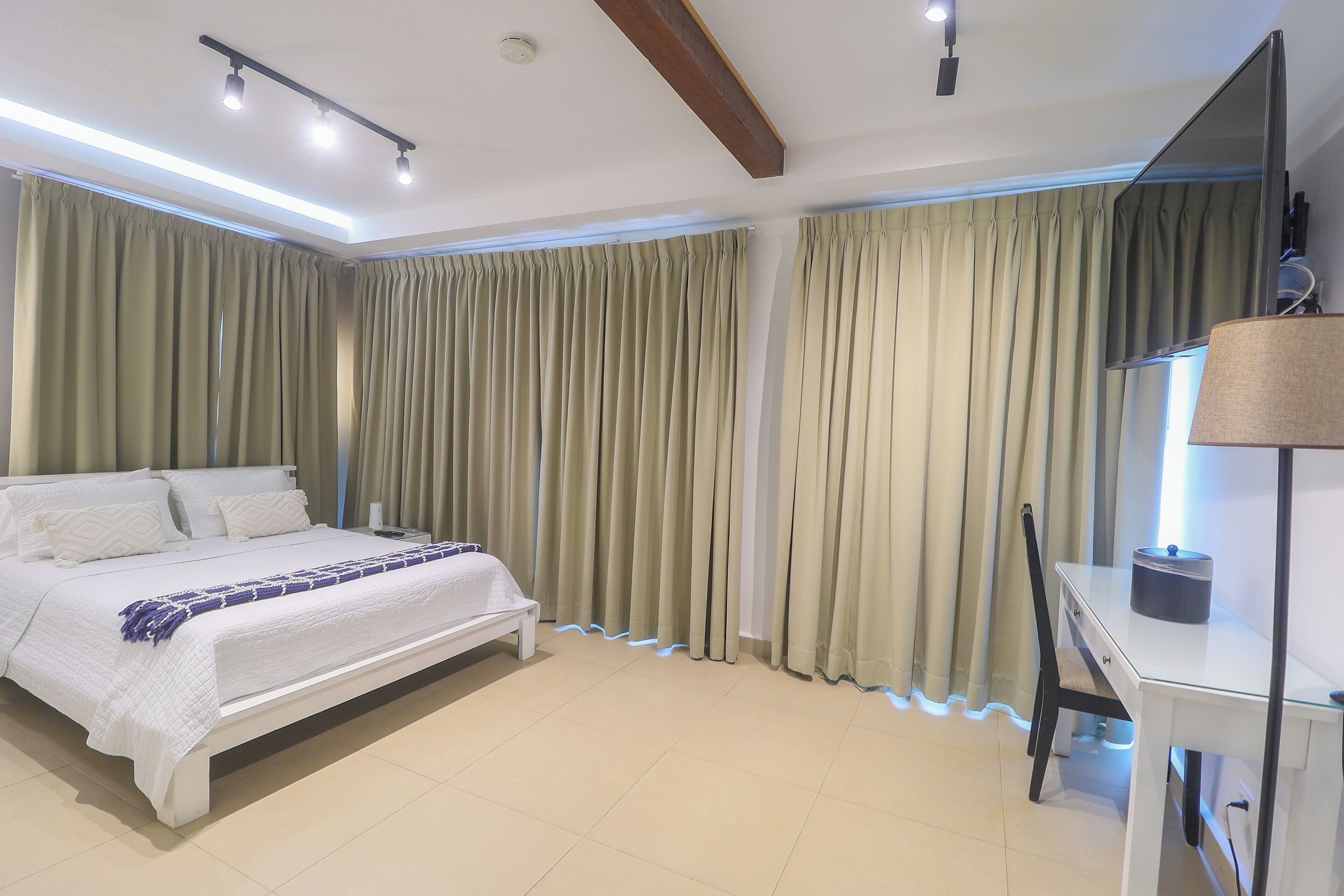A modern bedroom with a bed, a desk, and curtains.