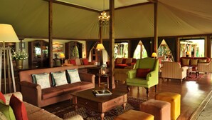 A spacious tented lounge area with a variety of seating options, including sofas and armchairs, and a central coffee table.