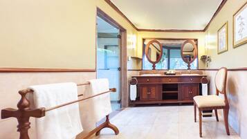 A bathroom with a wooden vanity, a large mirror, a towel rack, and a chair.