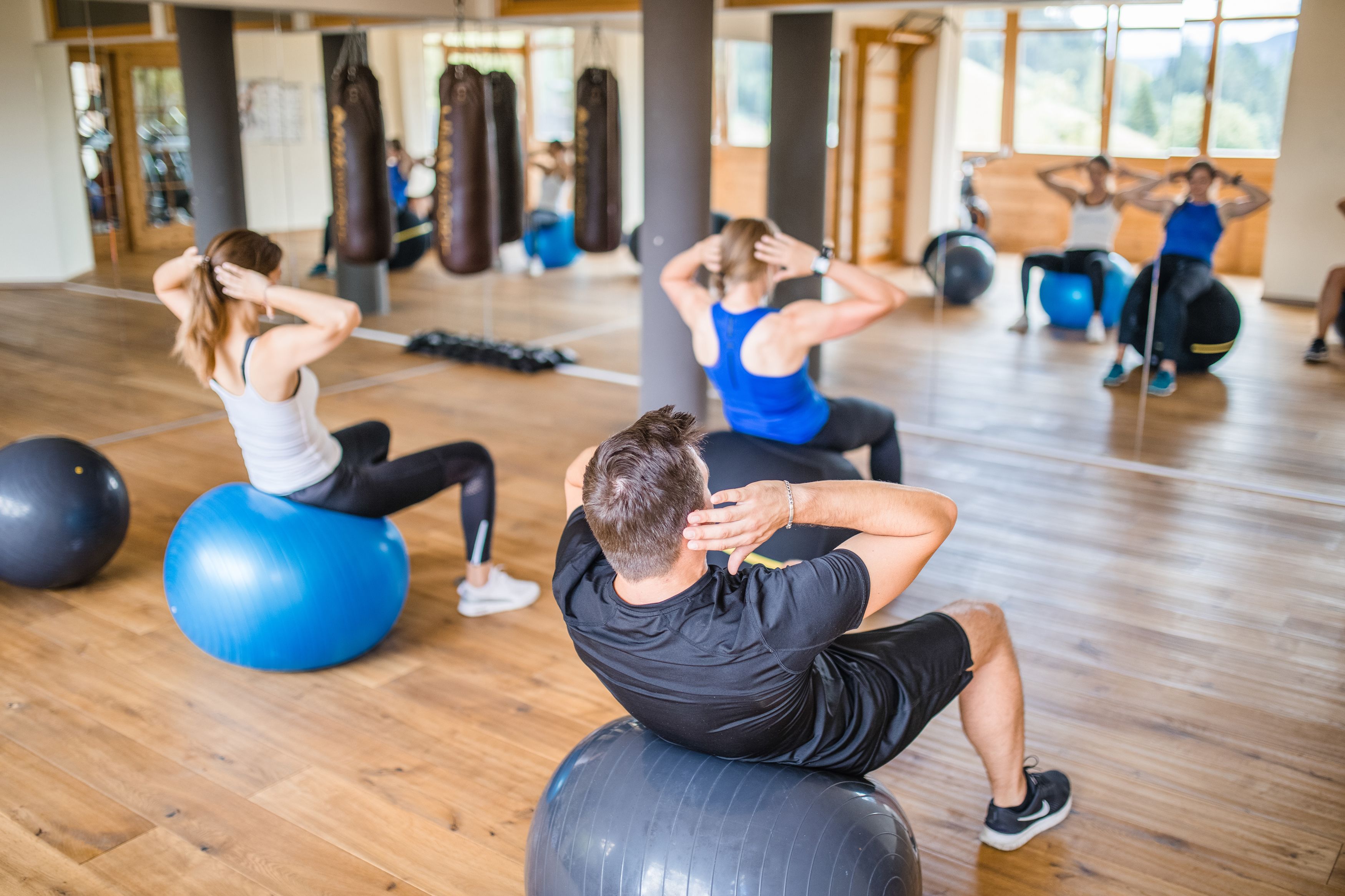 Et fitnessrum med træningsbolde, boksehandsker og trægulv.