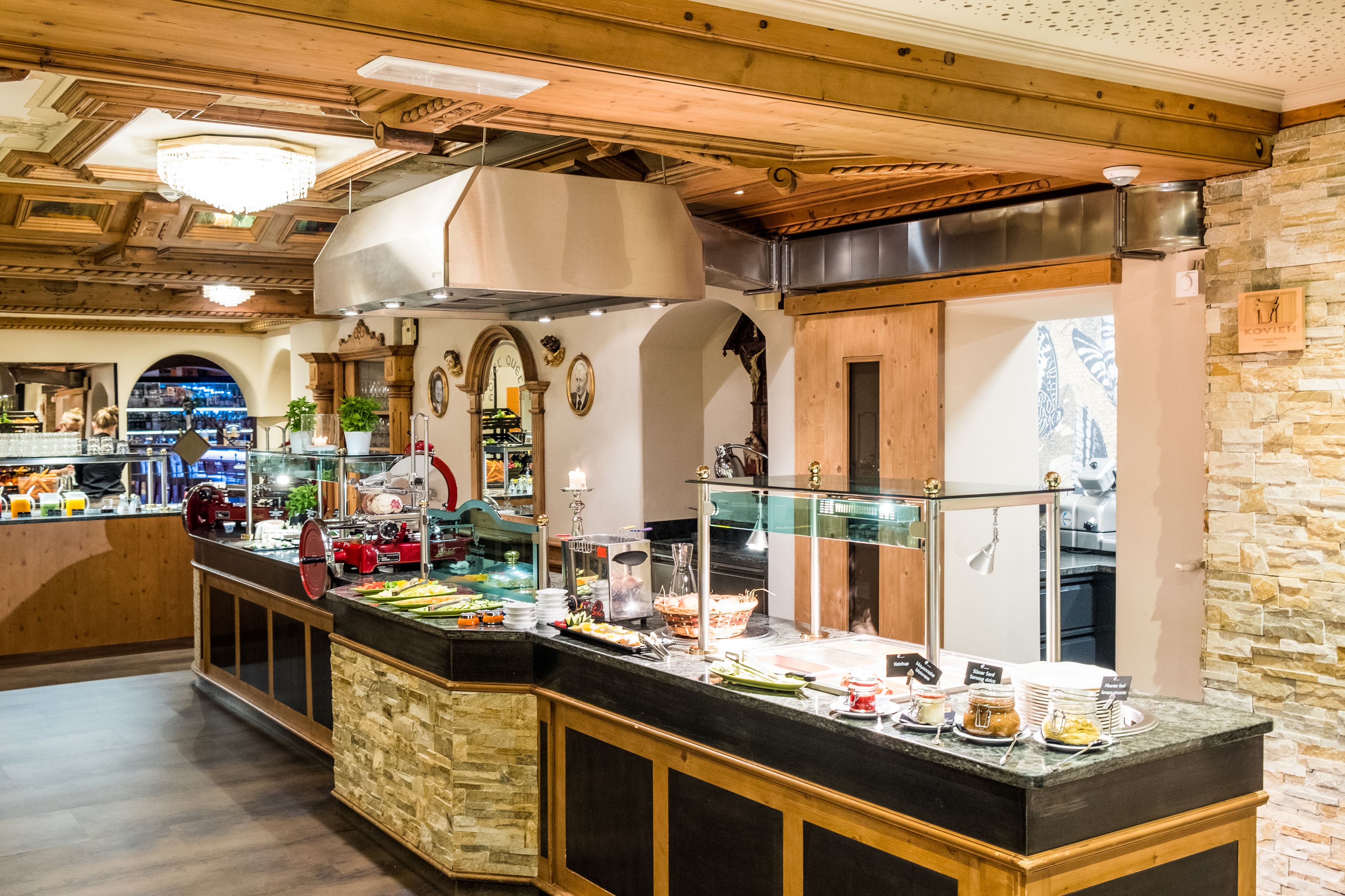 A buffet area with a variety of food items, a stone wall, and wooden ceiling beams.
