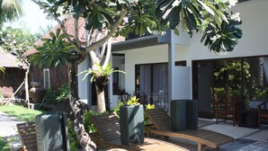 A patio with wooden lounge chairs, a potted plant, and a small table. - Alam Bali Hotel (Nusa Dua)